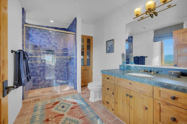 bathroom featuring tile patterned flooring, vanity, toilet, and a shower with door