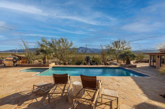 view of swimming pool with a mountain view, a patio area, and a grill