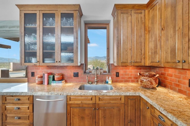 kitchen with dishwasher, tasteful backsplash, light stone counters, and sink