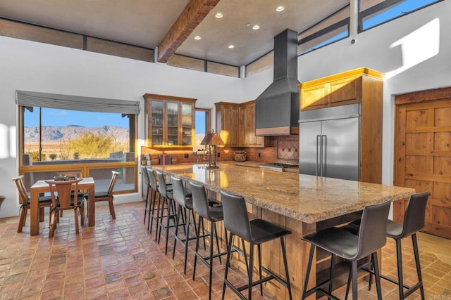 kitchen featuring premium range hood, light stone countertops, appliances with stainless steel finishes, tasteful backsplash, and beam ceiling