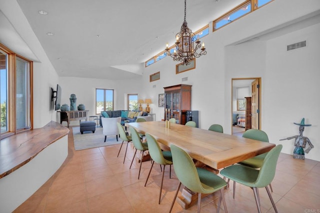 dining space featuring light tile patterned flooring, a chandelier, and a high ceiling