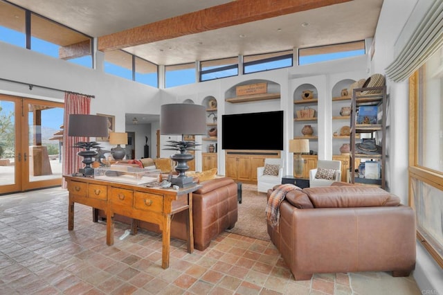 living room featuring beamed ceiling, french doors, built in shelves, and a high ceiling