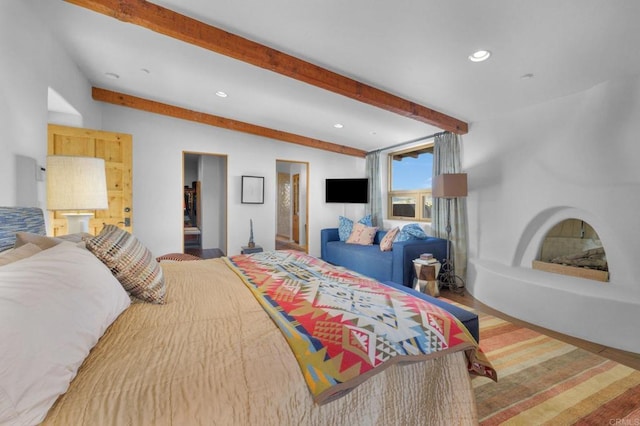 bedroom with beamed ceiling, ensuite bathroom, and wood-type flooring