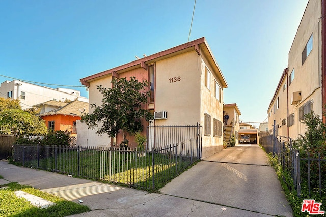 view of front of home with a front lawn and a wall unit AC