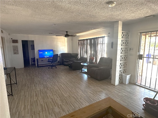 living room featuring ceiling fan, hardwood / wood-style flooring, and a textured ceiling