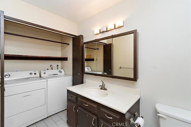 bathroom with toilet, vanity, and washer and dryer