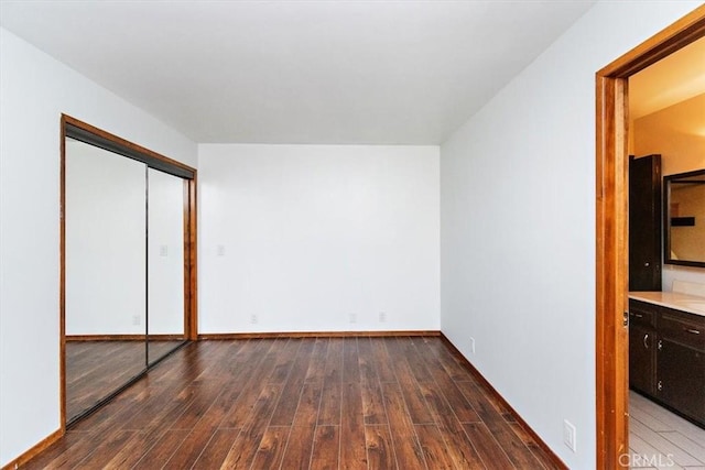 unfurnished bedroom with a closet, dark hardwood / wood-style floors, and ensuite bath