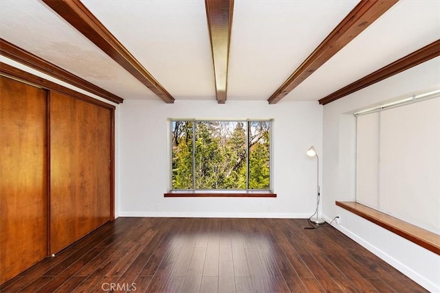 unfurnished bedroom with a closet, beam ceiling, and dark hardwood / wood-style floors