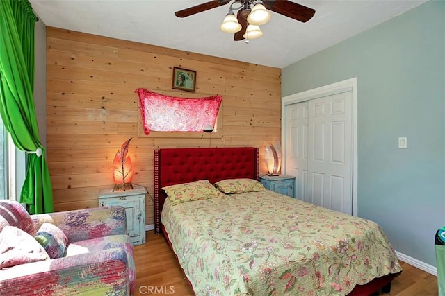 bedroom with hardwood / wood-style flooring, a closet, wooden walls, and ceiling fan