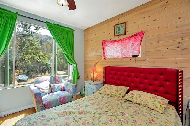 bedroom with wooden walls, ceiling fan, and wood-type flooring