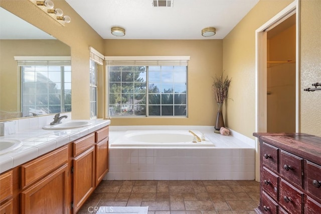 bathroom with vanity and tiled bath