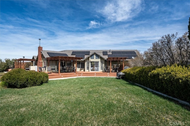 rear view of house with solar panels, a yard, and a patio area