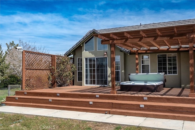 rear view of property featuring a wooden deck and a covered hot tub