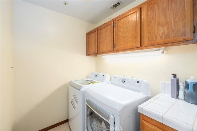 laundry area with washer and clothes dryer and cabinets