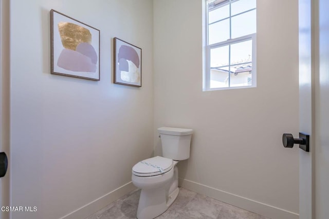 bathroom with tile patterned flooring, toilet, and a healthy amount of sunlight