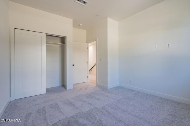 unfurnished bedroom featuring light colored carpet and a closet