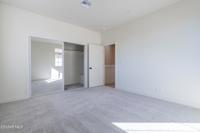 unfurnished bedroom with a closet and light colored carpet