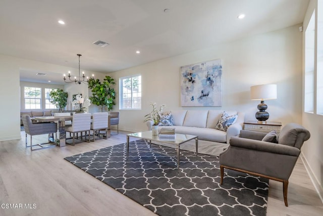 living room featuring a chandelier, light hardwood / wood-style flooring, and plenty of natural light