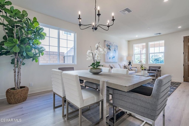 dining space featuring plenty of natural light, light hardwood / wood-style floors, and an inviting chandelier