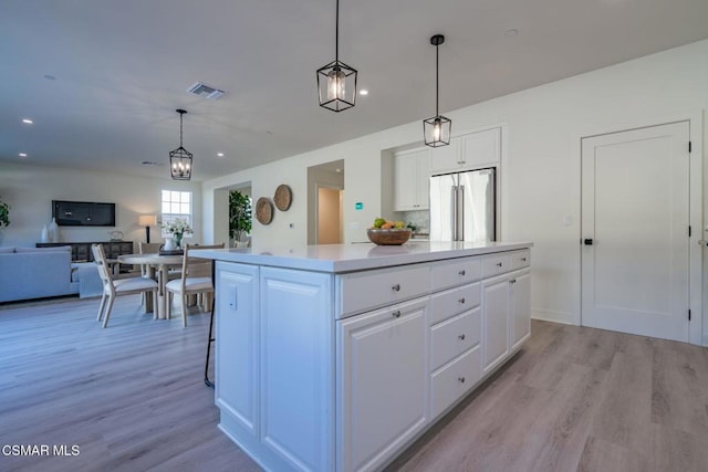 kitchen featuring high end refrigerator, a center island, light hardwood / wood-style floors, white cabinetry, and hanging light fixtures