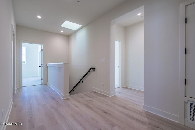 hall featuring light hardwood / wood-style flooring and a skylight