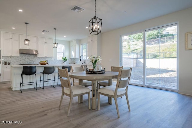 dining space featuring plenty of natural light, a notable chandelier, and light hardwood / wood-style flooring