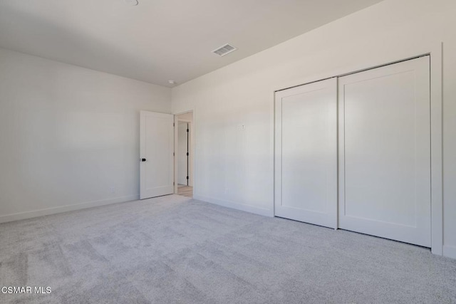 unfurnished bedroom featuring light colored carpet and a closet