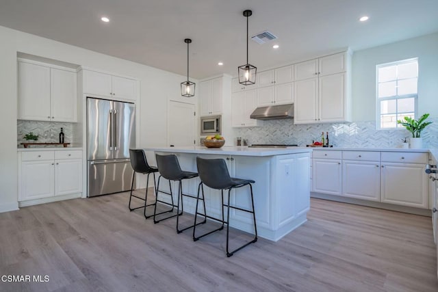 kitchen with built in appliances, light hardwood / wood-style flooring, white cabinetry, and a kitchen island