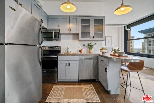 kitchen with appliances with stainless steel finishes, decorative backsplash, a breakfast bar, kitchen peninsula, and sink