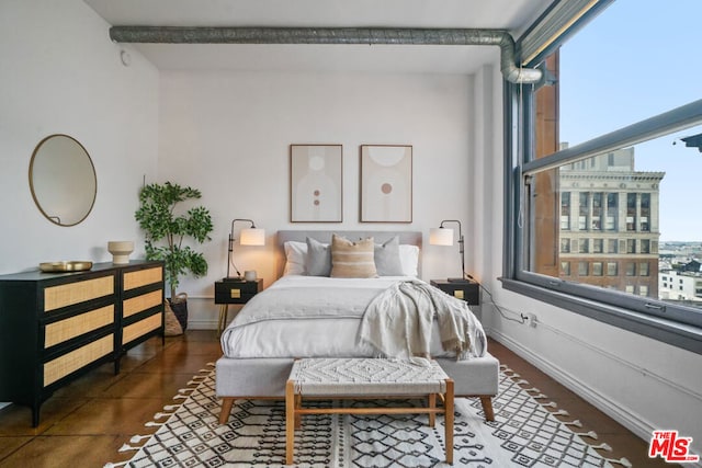 bedroom with dark tile patterned flooring and beamed ceiling