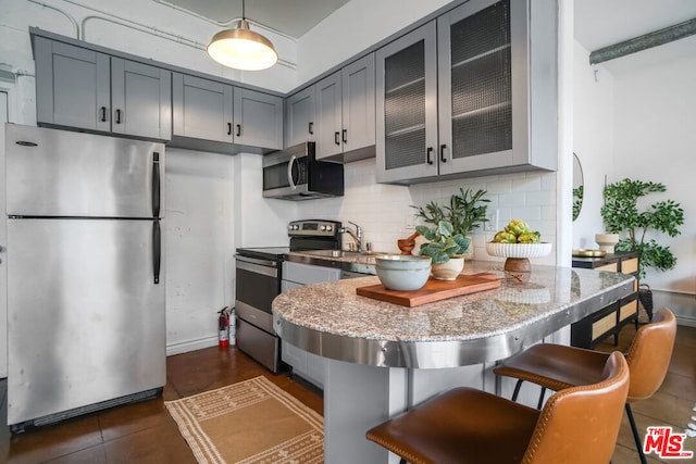 kitchen featuring dark tile patterned floors, sink, tasteful backsplash, appliances with stainless steel finishes, and dark stone countertops