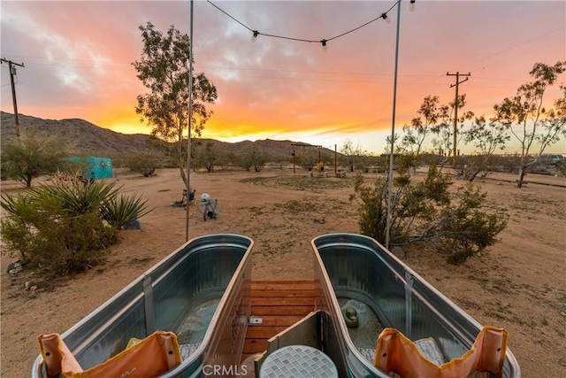 yard at dusk with a mountain view and a jacuzzi