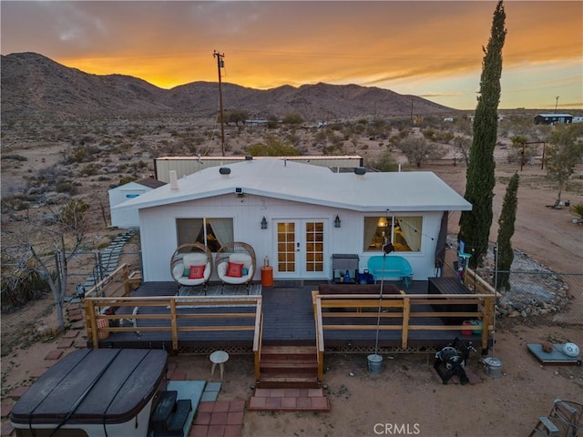 back house at dusk featuring a deck with mountain view and french doors