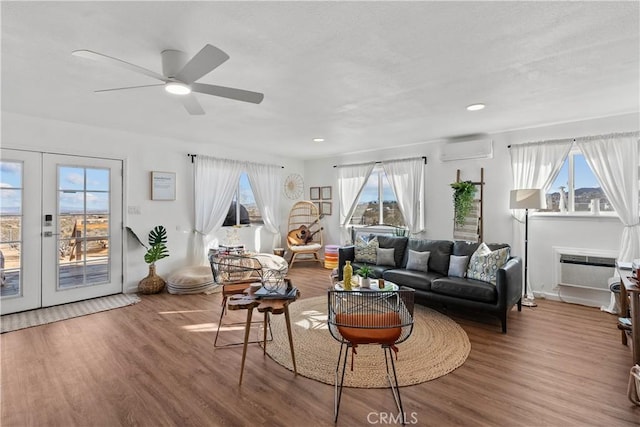 living room with ceiling fan, wood-type flooring, an AC wall unit, and french doors