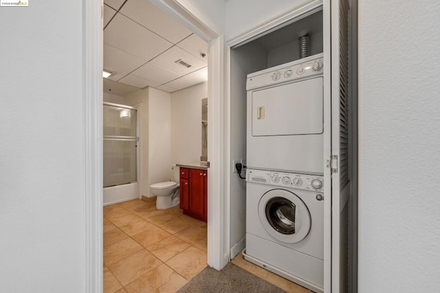 laundry room featuring stacked washer / drying machine and light tile patterned flooring