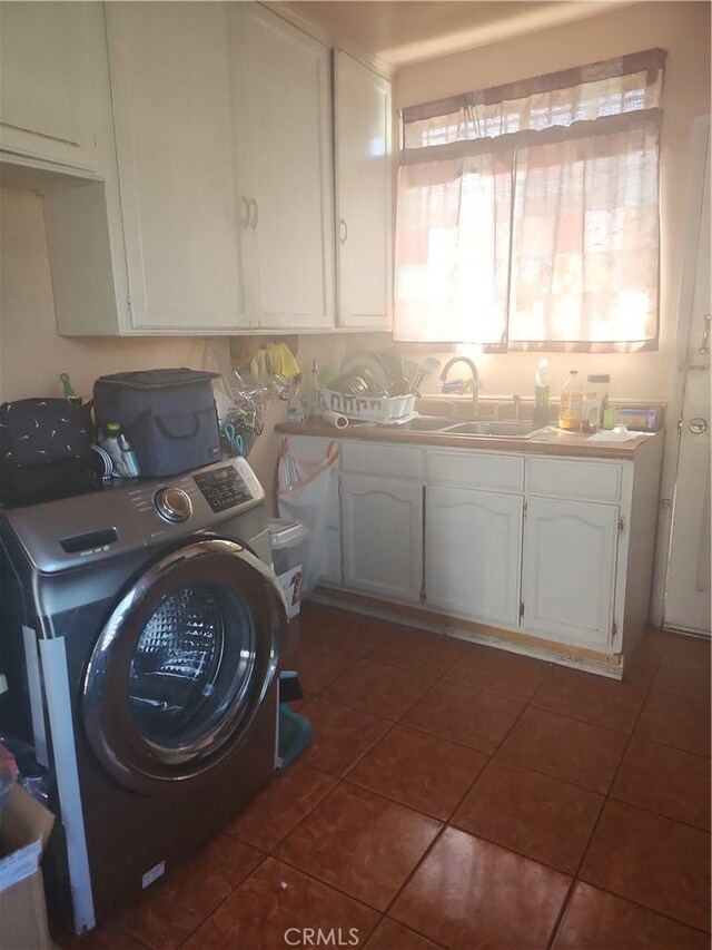 clothes washing area with washer / clothes dryer, dark tile patterned flooring, sink, and cabinets