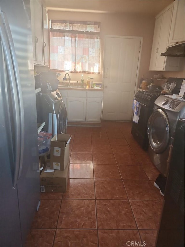 clothes washing area with dark tile patterned floors, sink, independent washer and dryer, and cabinets