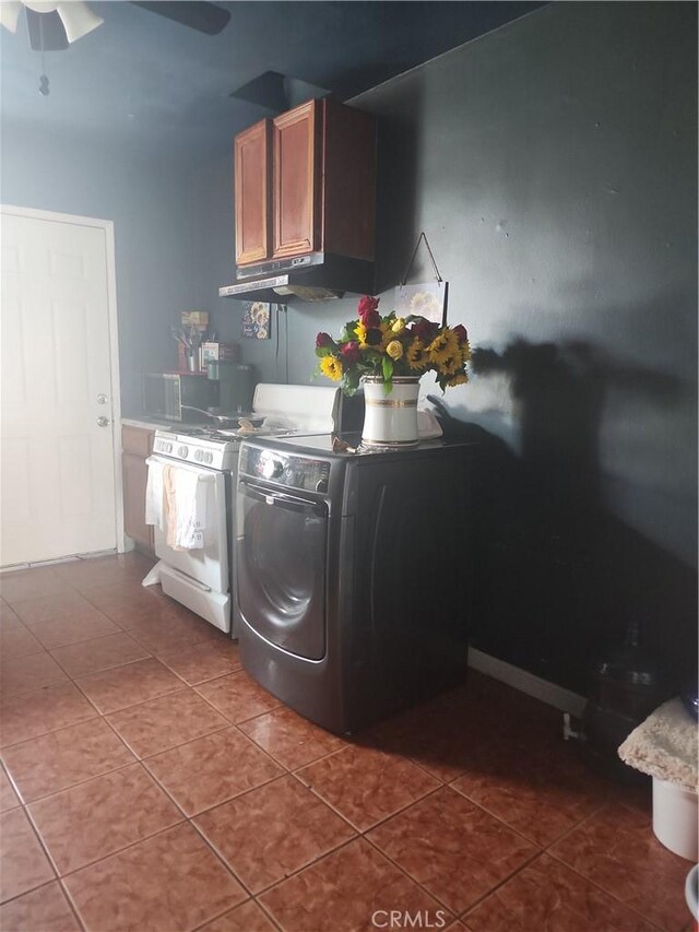 laundry room with washer and dryer, cabinets, dark tile patterned flooring, and ceiling fan