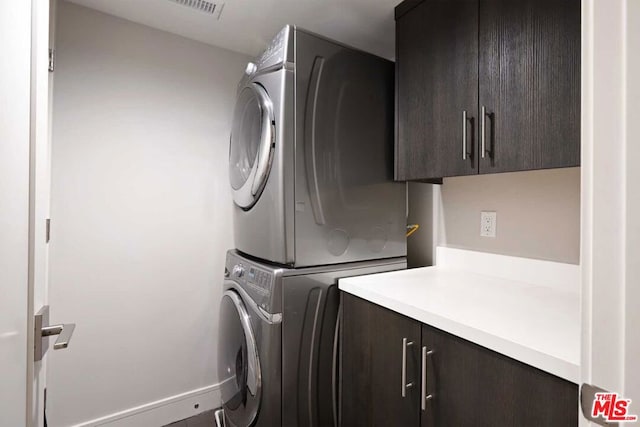 laundry room with stacked washer and clothes dryer and cabinets