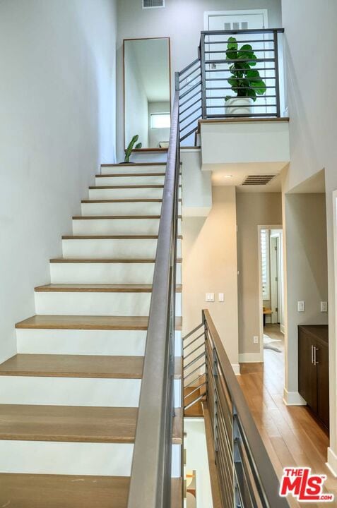 stairway featuring hardwood / wood-style floors and a high ceiling