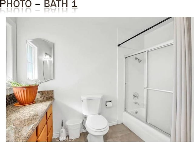 bathroom featuring tile patterned flooring, vanity, toilet, and bath / shower combo with glass door