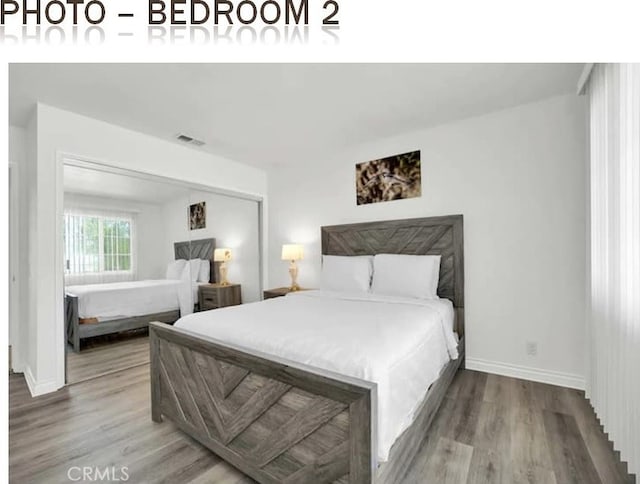 bedroom featuring visible vents, baseboards, and wood finished floors