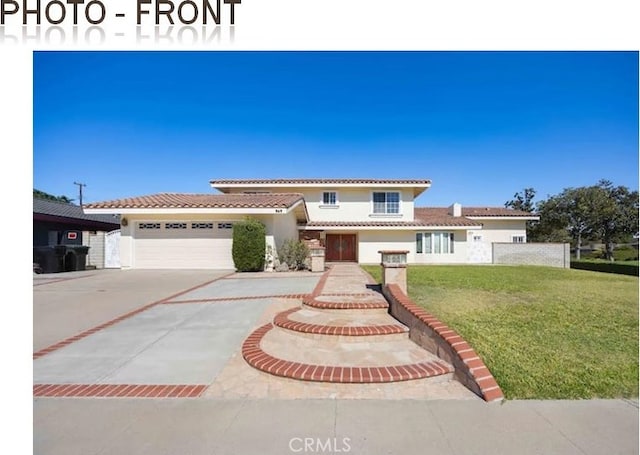 mediterranean / spanish-style home with stucco siding, concrete driveway, an attached garage, a front yard, and a tiled roof