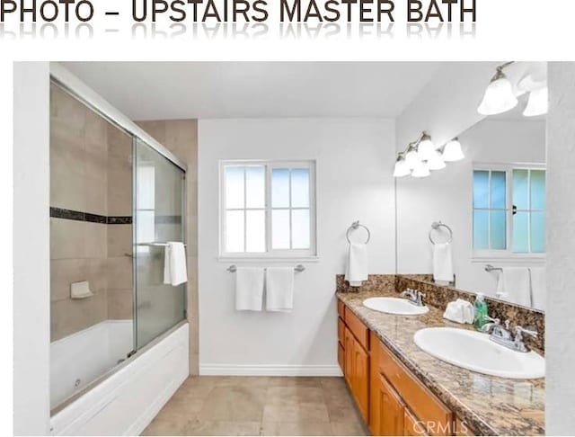 full bathroom featuring enclosed tub / shower combo, double vanity, a sink, and baseboards