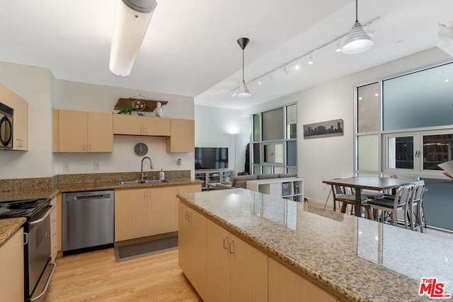 kitchen with hanging light fixtures, sink, appliances with stainless steel finishes, light brown cabinetry, and light hardwood / wood-style floors