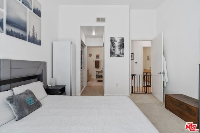 carpeted bedroom featuring connected bathroom and white fridge