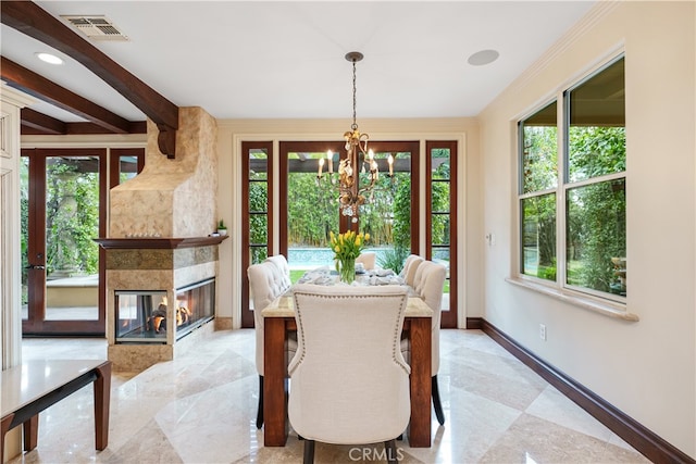 dining area with a stone fireplace, an inviting chandelier, and plenty of natural light