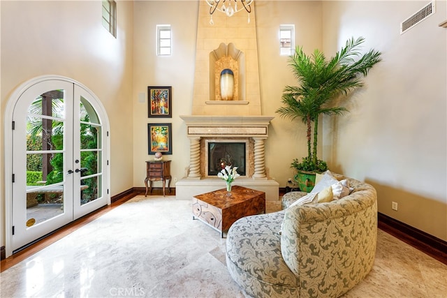 sitting room featuring french doors, a notable chandelier, and a fireplace