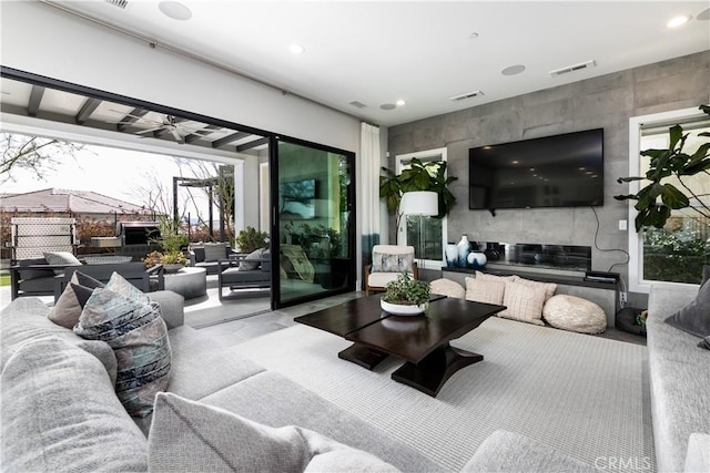 living room with a tiled fireplace and ceiling fan