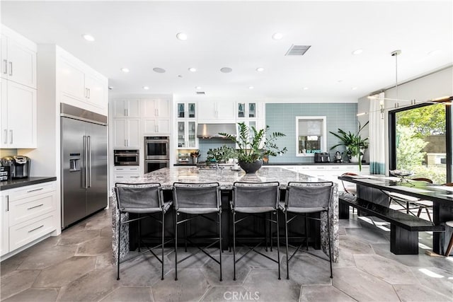 kitchen featuring pendant lighting, stainless steel appliances, a kitchen island with sink, and a breakfast bar area